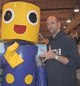 DMZ: Dystopian Visions of Post-9/11 America (image credits: From the English-speaking wikipedia. There, Rootology submited it under {{PD-self}}, with the following description:

Photo of Brian Wood, Boston comic con, 2002. I took this. No idea what the horrible that thing next to him is, but it is cute., Public domain, https://commons.wikimedia.org/w/index.php?curid=1692330)